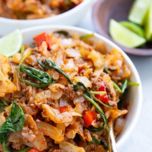 Two bowls of Ground Beef and Cabbage with a gold spoon, ready to eat.