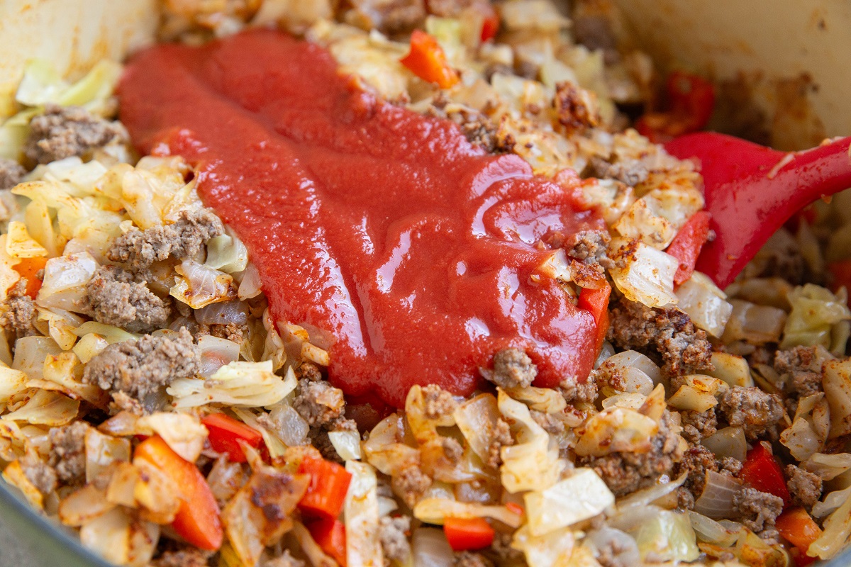 Tomato sauce in a large pot with meat and veggies, ready to be mixed in.