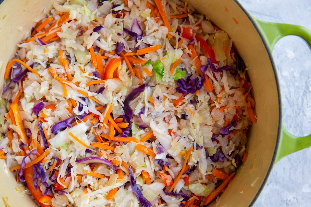 Big pot of cabbage, carrots, onions, and bell peppers cooking.