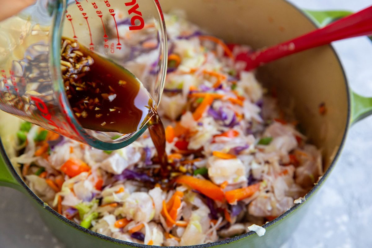 Pouring the homemade sauce into the pot with the chicken and veggies.