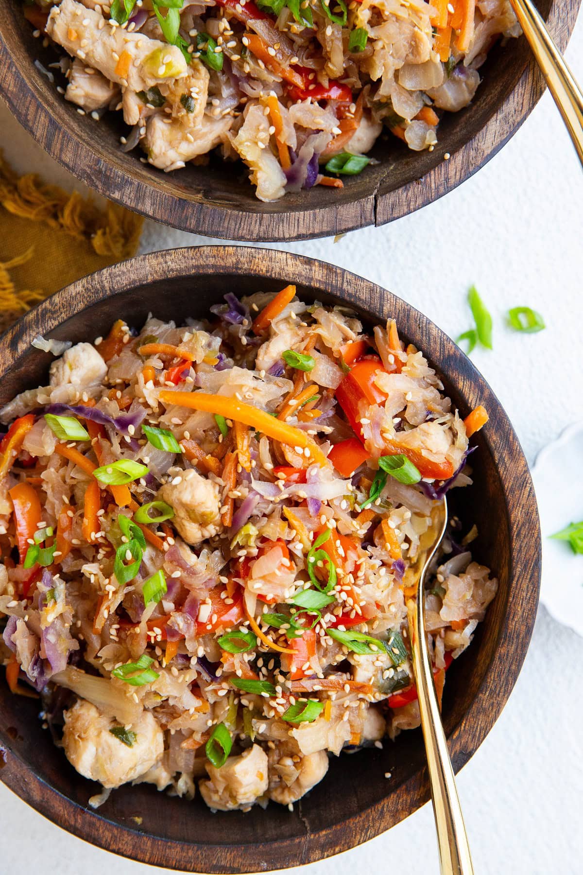 Two wooden bowls of chicken and vegetables, ready to eat.