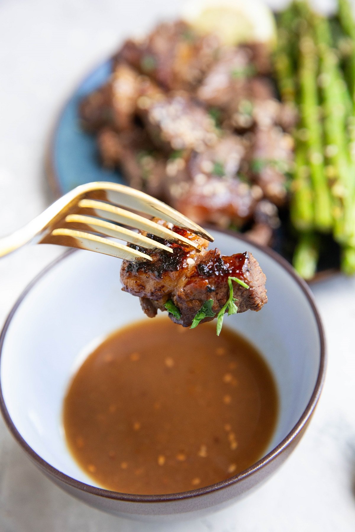 Fork holding a steak bite that was dipped in teriyaki sauce.