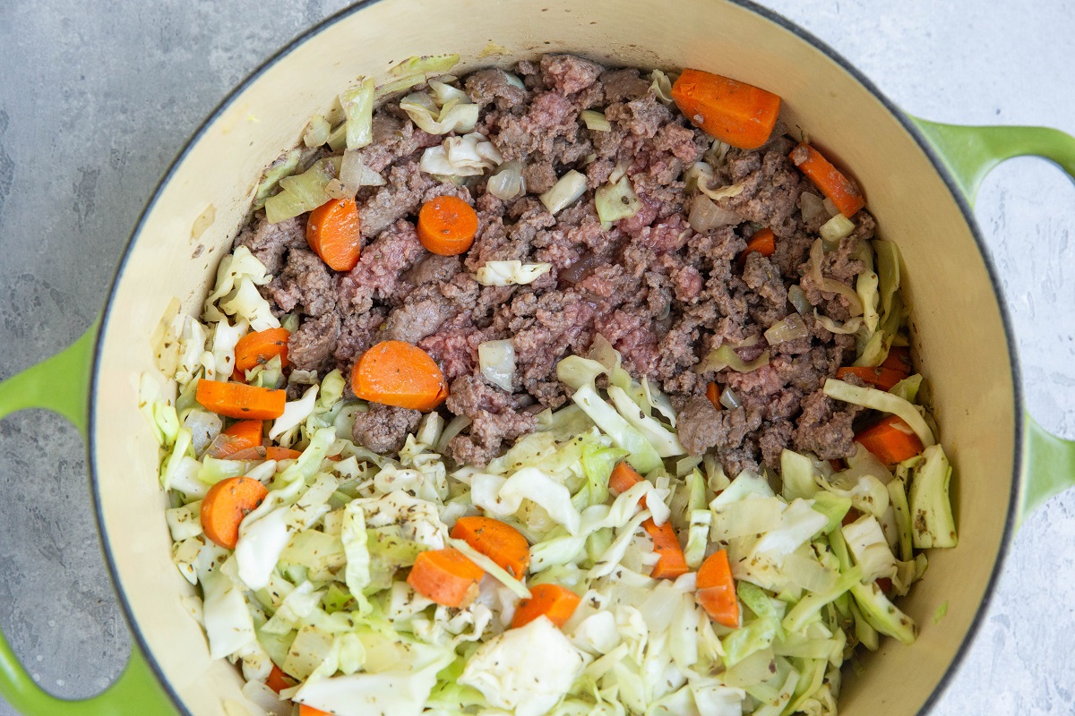 Ground beef, cabbage, and carrots cooking in a large pot.