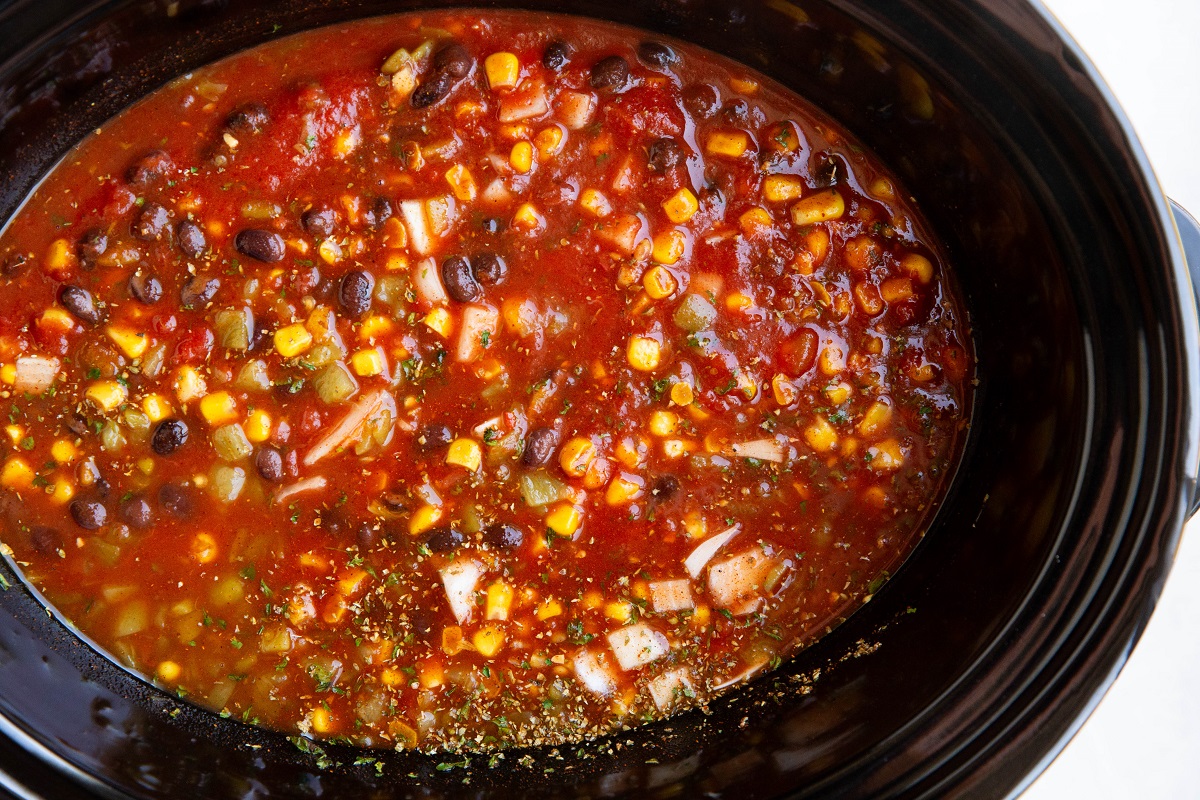 Ingredients for tortilla soup stirred in a crock pot, ready to cook.