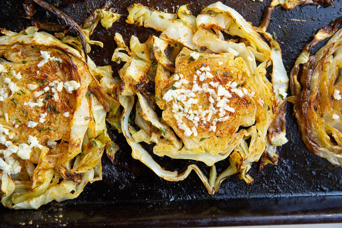 Baking sheet with cabbage rounds with garlic butter spread on top.