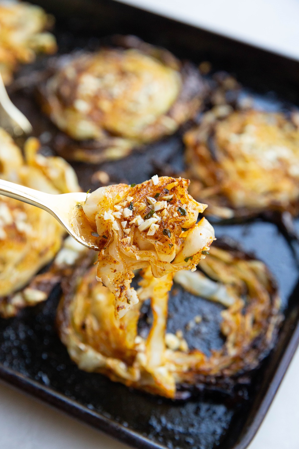 Fork holding a forkful of roasted cabbage.