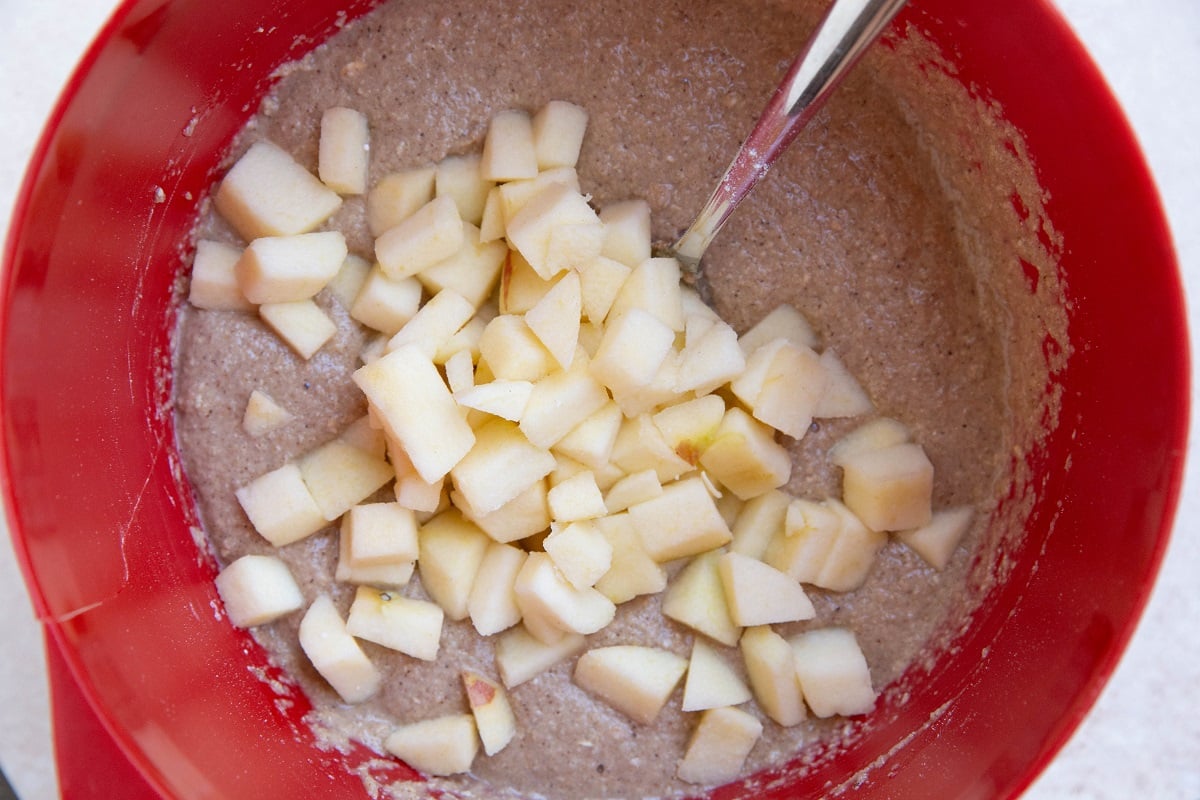 Oatmeal bread batter with chopped apples on top, ready to be mixed in.
