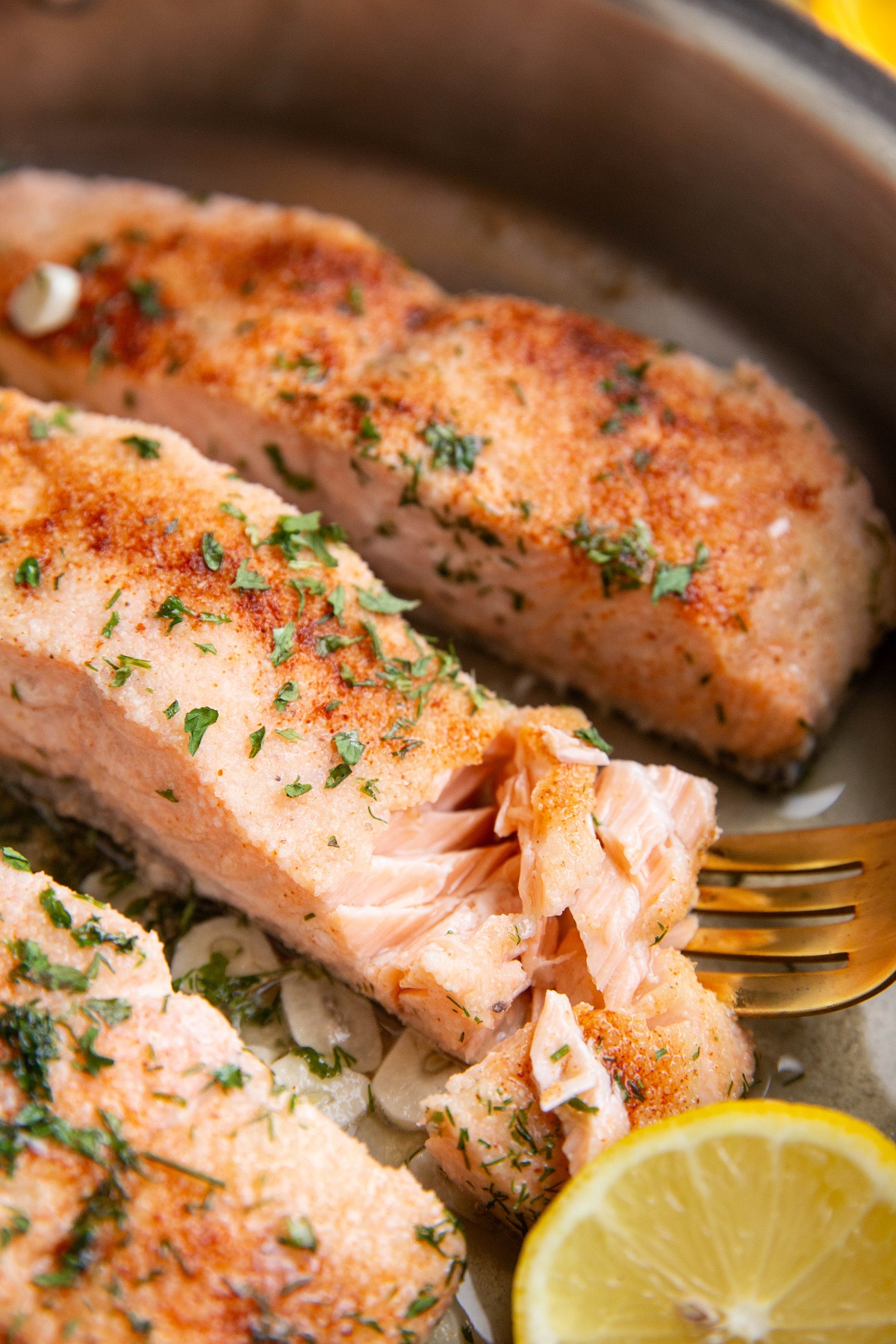 Fork taking a bite out of poached salmon, revealing the juicy inside.