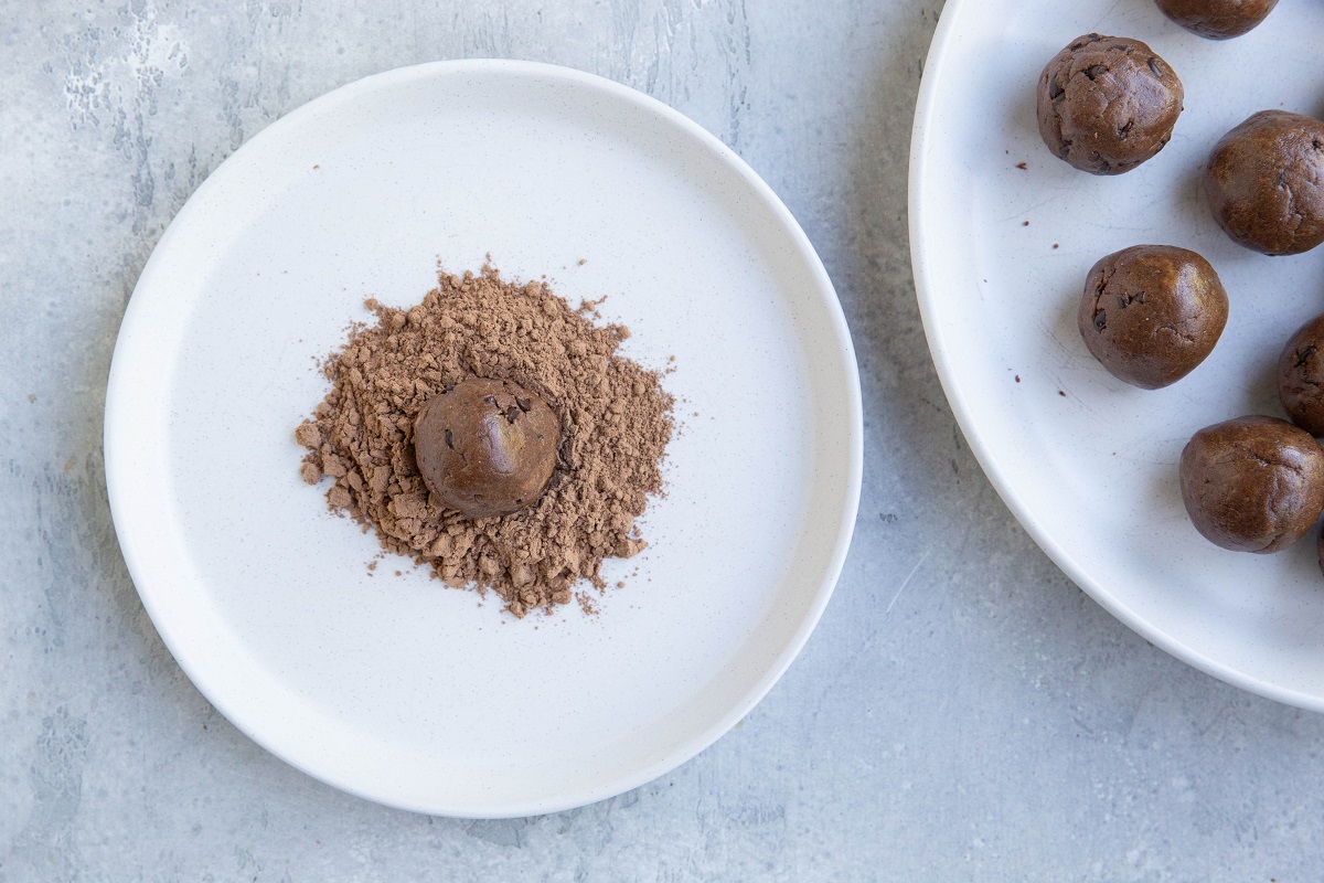 protein ball on a pile of cocoa powder, ready to be rolled.