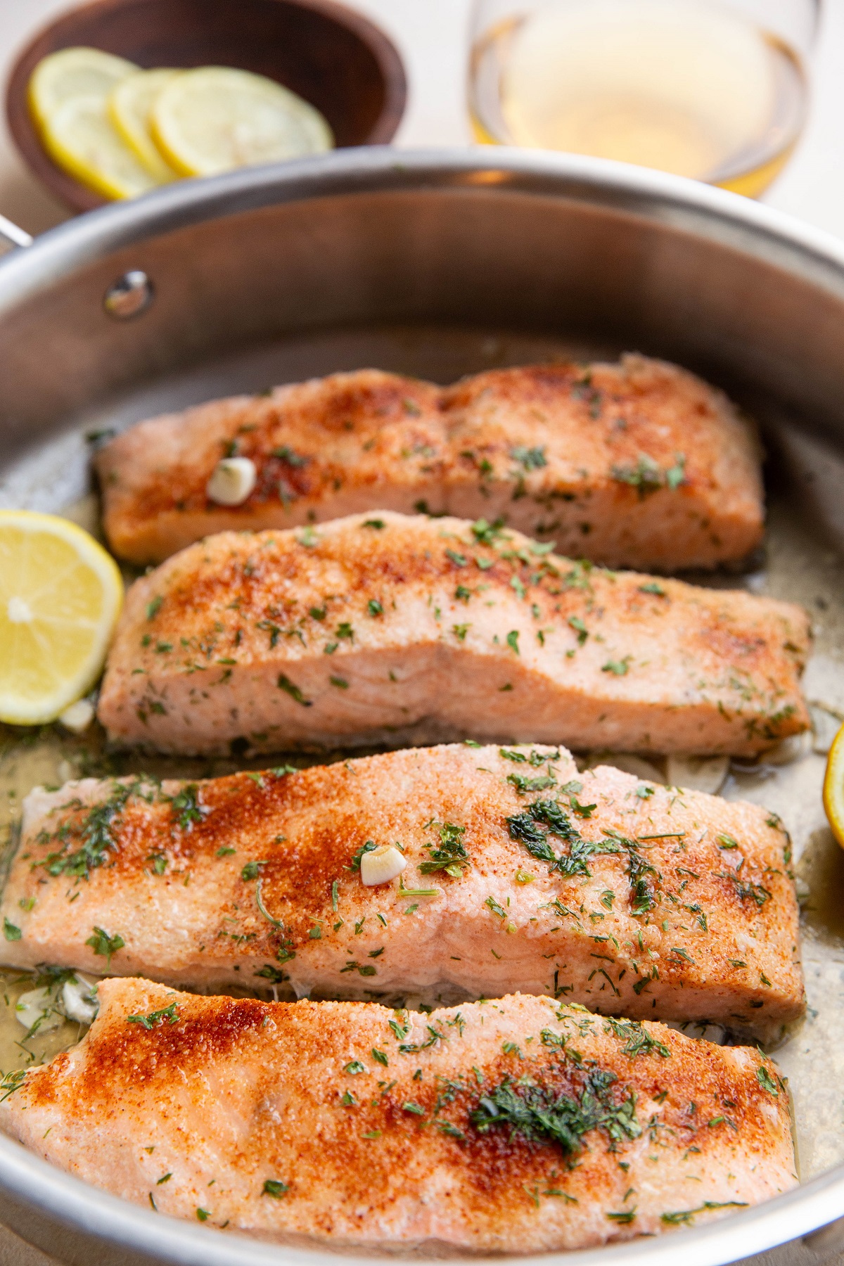 Four cooked salmon filers in a skillet, ready to serve.