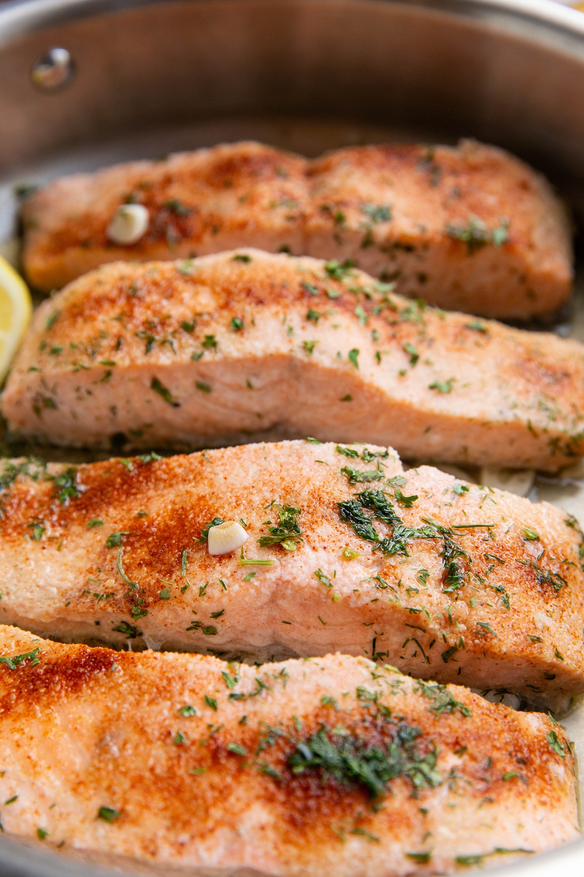 Poached salmon in a skillet, ready to eat with side dishes.