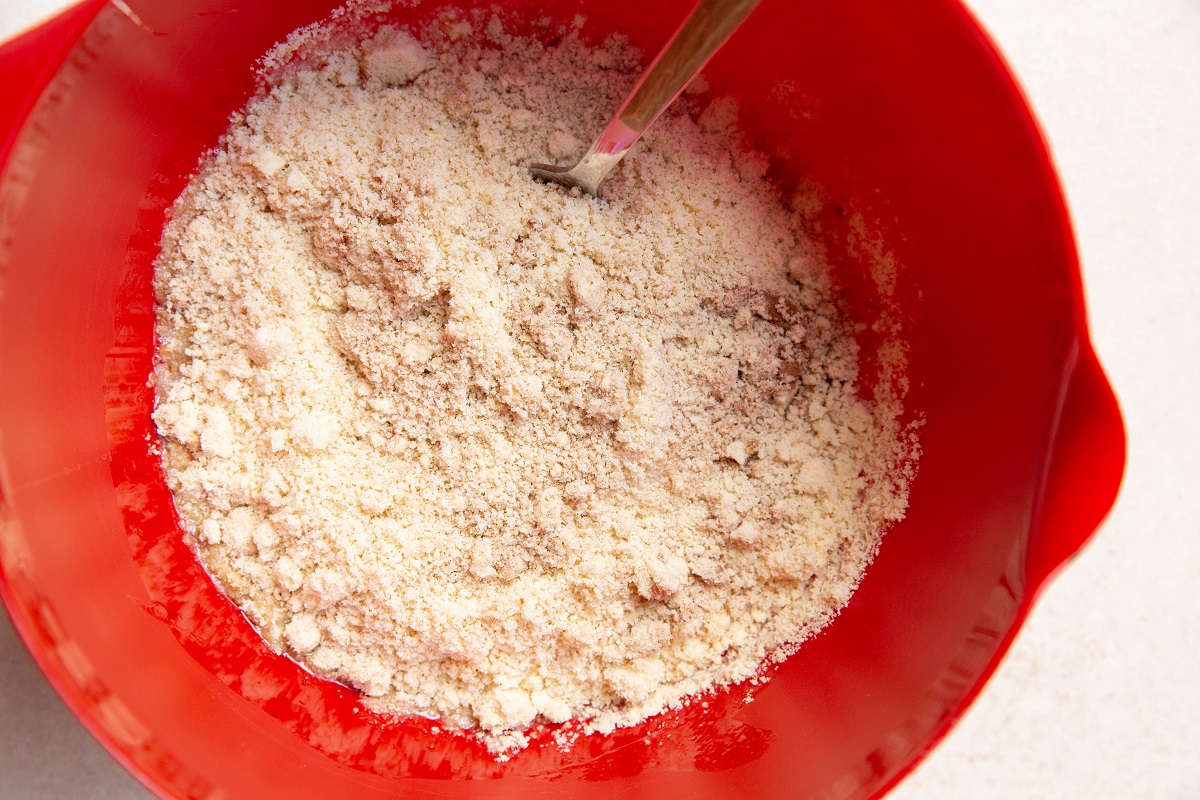 Dry ingredients on top of wet ingredients in a mixing bowl to make carrot apple muffins.