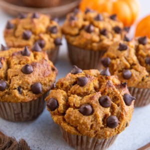 Almond Flour pumpkin muffins on a plate, ready to serve, with small pumpkins in the background.