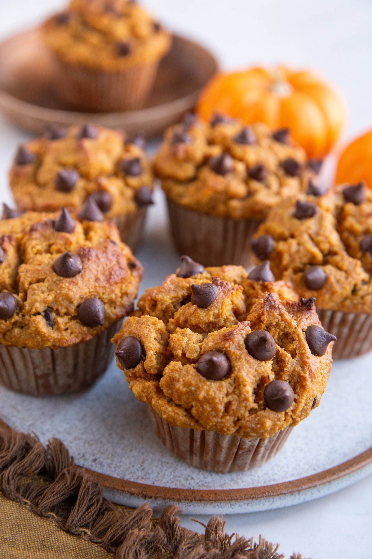 Almond Flour pumpkin muffins on a plate, ready to serve, with small pumpkins in the background.