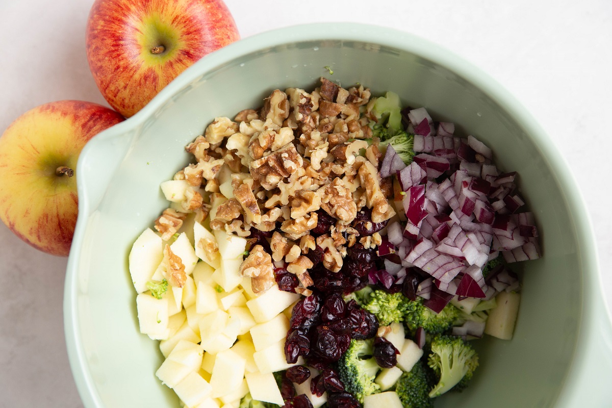 Ingredients for apple broccoli salad in a mixing bowl