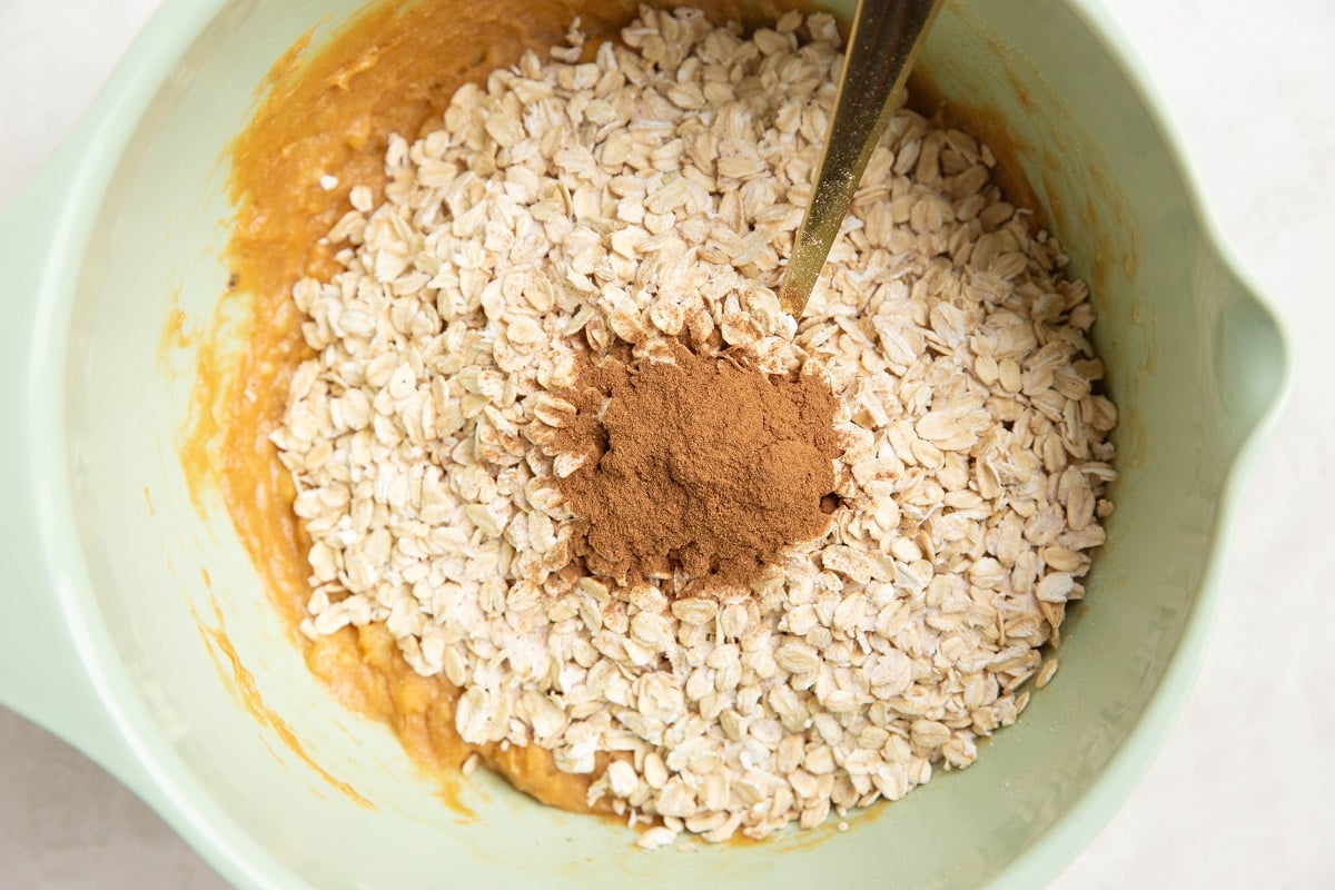 Oats on top of banana peanut butter mixture, ready to be mixed in.