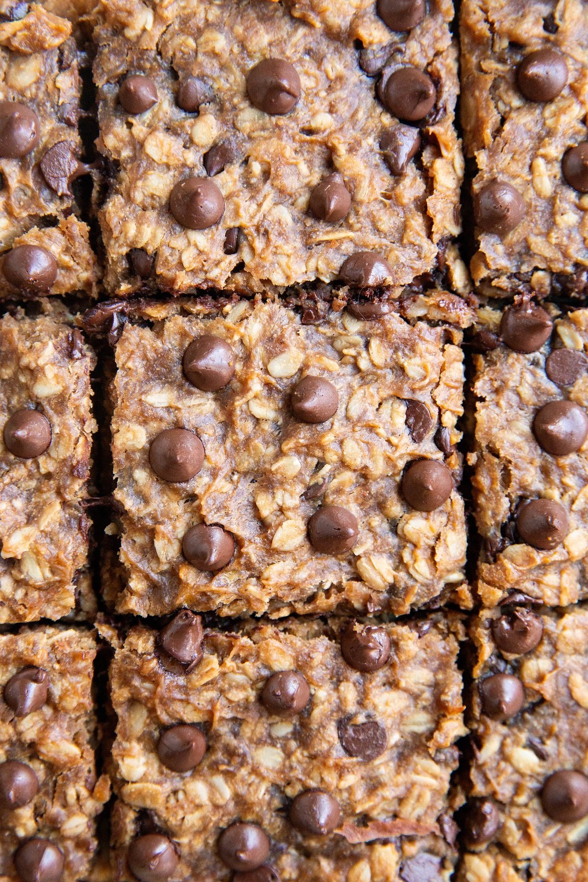 Slices of peanut butter chocolate chip banana oatmeal bars on a sheet of parchment paper.