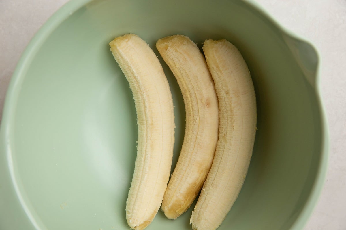 Three ripe bananas in a mixing bowl, ready to be mashed