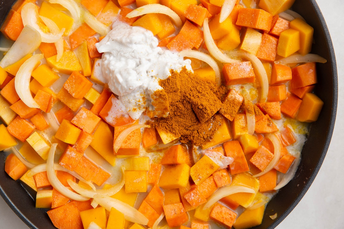 Butternut squash curry ingredients in a skillet, needing to be stirred.
