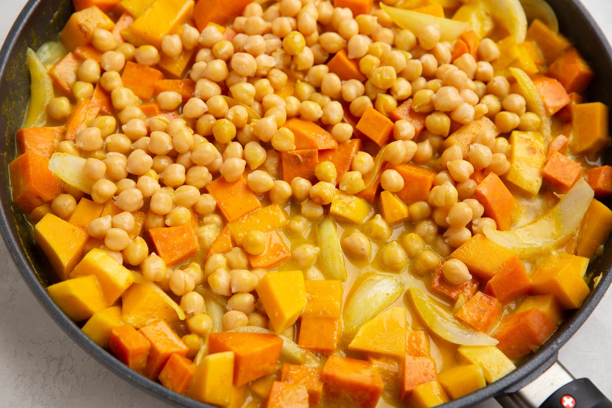 Butternut squash curry with chickpeas added on top, ready to be mixed in.