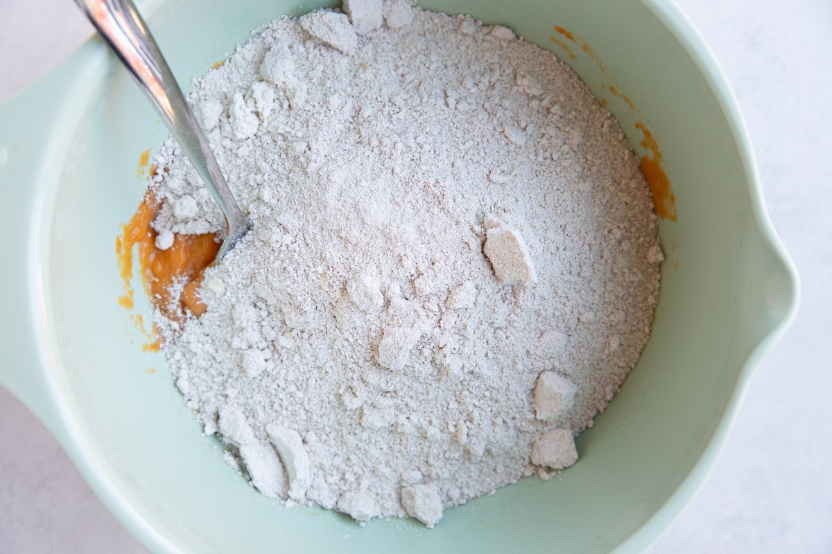 Oat flour on top of wet ingredients in a mixing bowl.