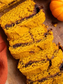 Cinnamon swirl pumpkin bread cut into slices on a wood cutting board.