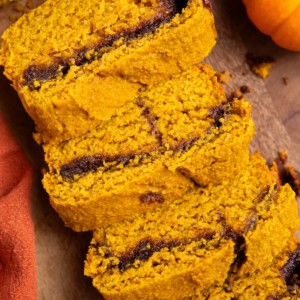 Cinnamon swirl pumpkin bread cut into slices on a wood cutting board.