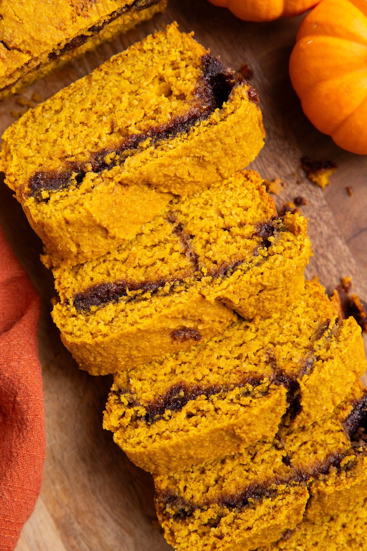 Cinnamon swirl pumpkin bread cut into slices on a wood cutting board.