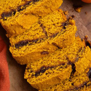 Cinnamon swirl pumpkin bread on a wooden cutting board cut into slices.