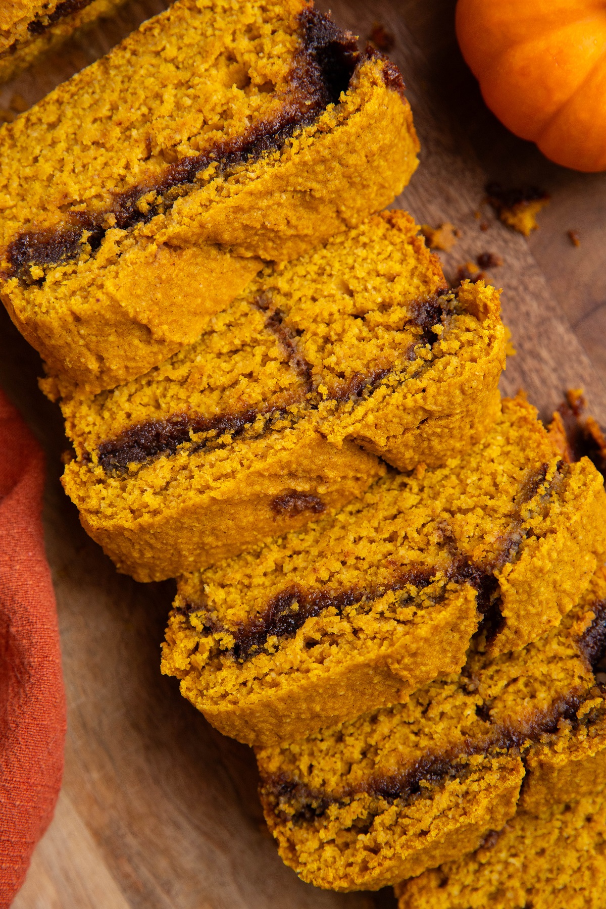 Cinnamon swirl pumpkin bread on a wooden cutting board cut into slices.