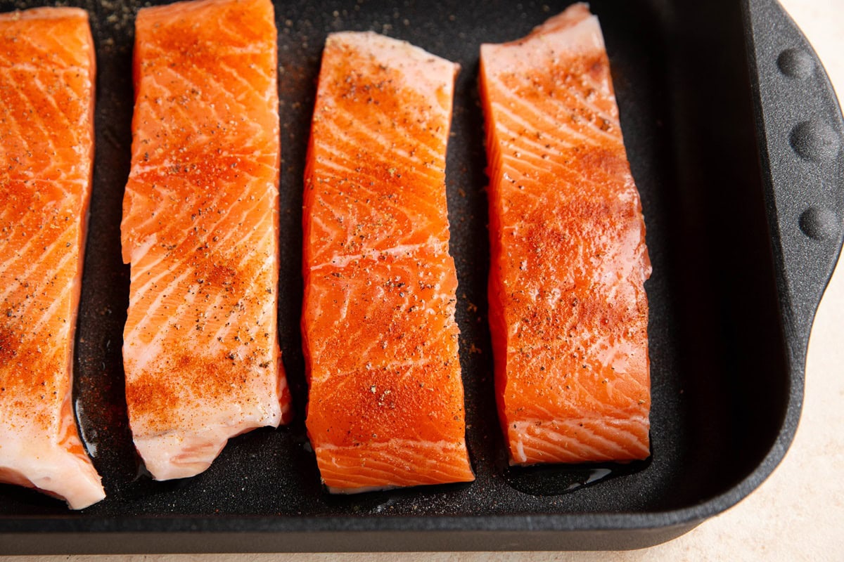 Salmon seasoned with salt and paprika in a casserole dish.