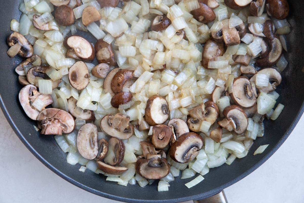 Skillet with onion and mushrooms cooking.