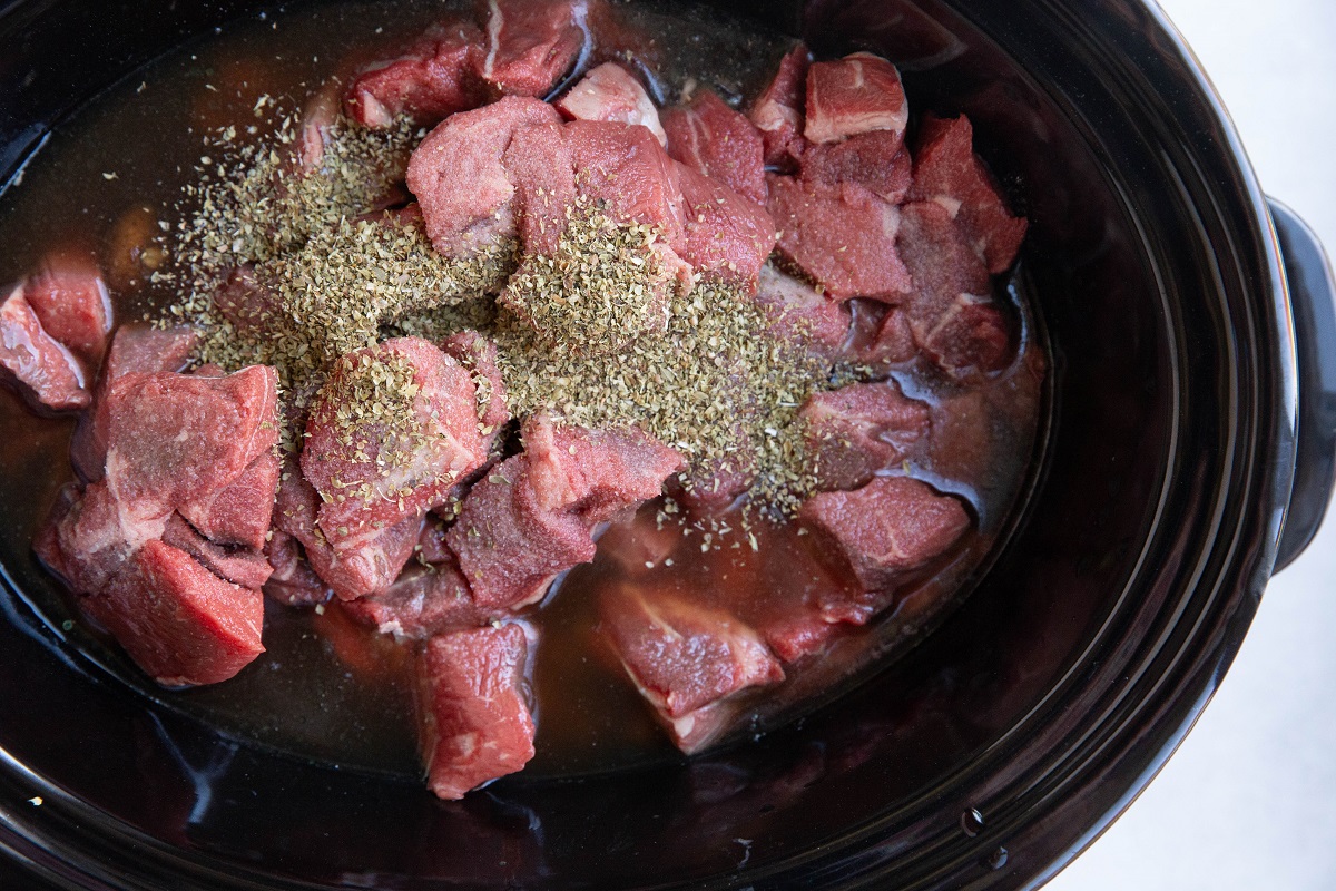 Beef in a crock pot with vegetables to make steak and potato soup.