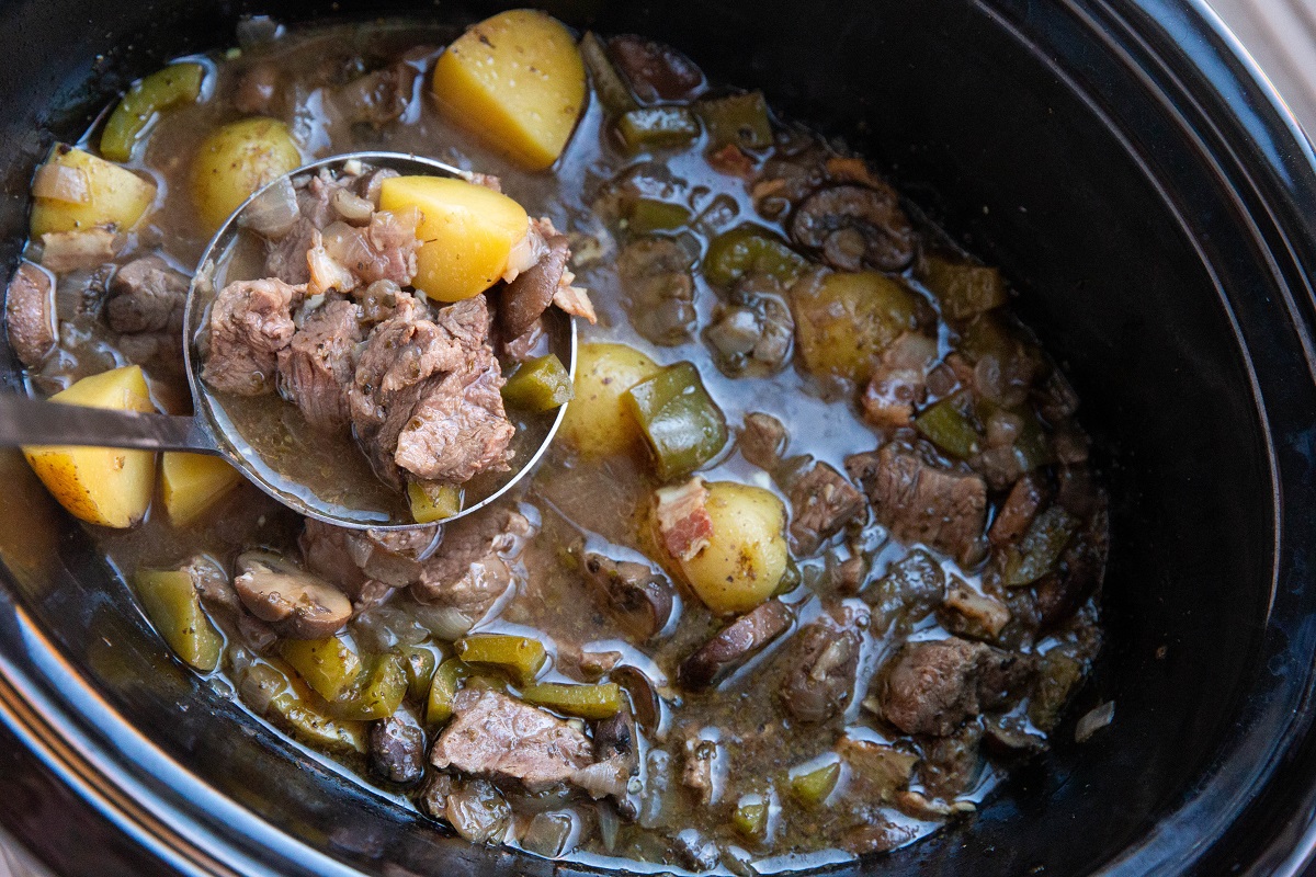 Crock pot with finished steak and potato soup inside.