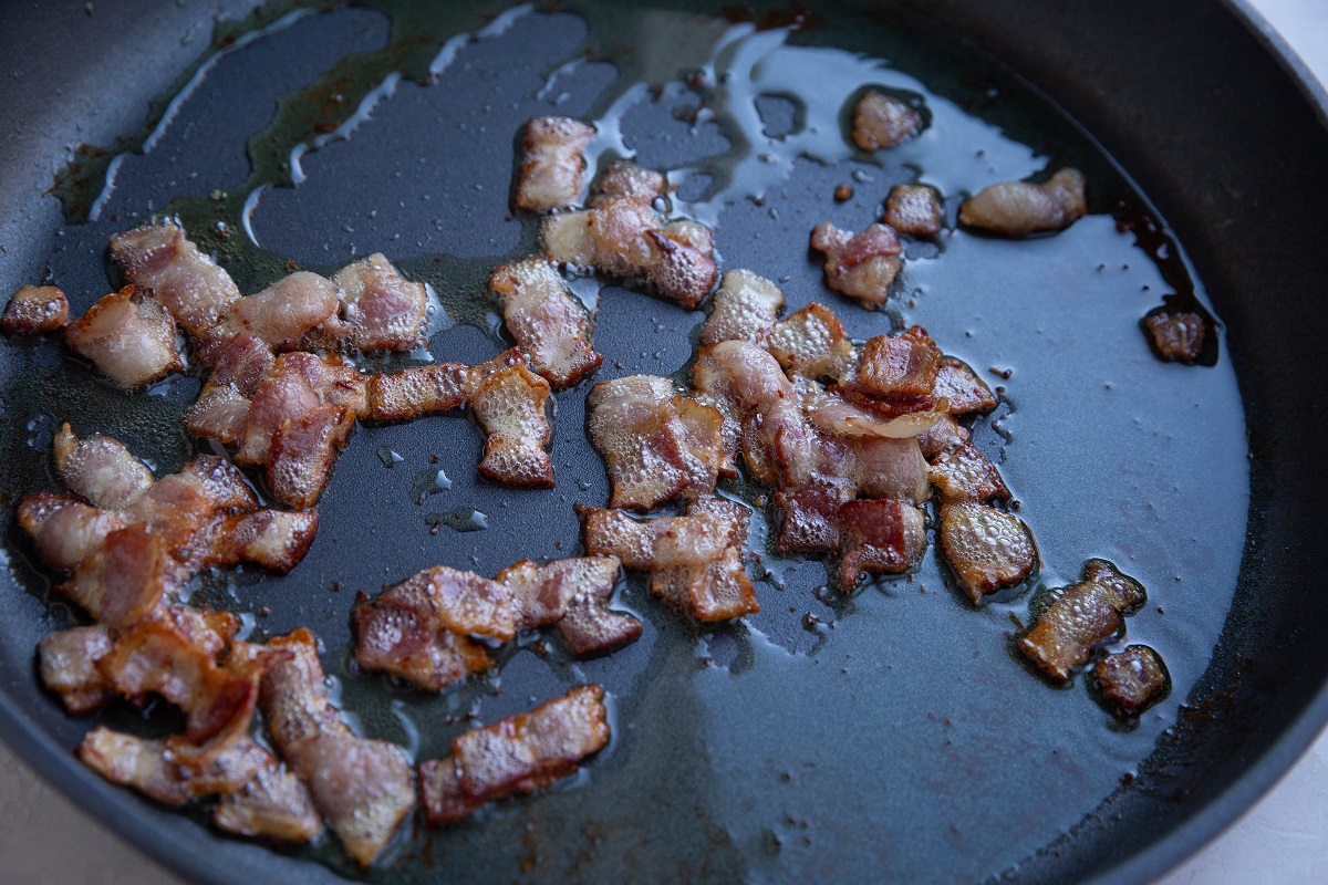 chopped bacon cooking in a skillet.