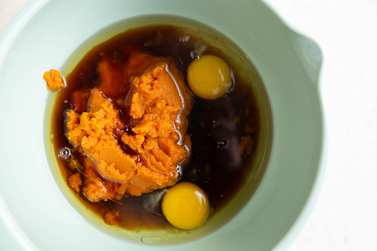Pumpkin puree, pure maple syrup, oil, and eggs in a mixing bowl to make chocolate pumpkin bread.