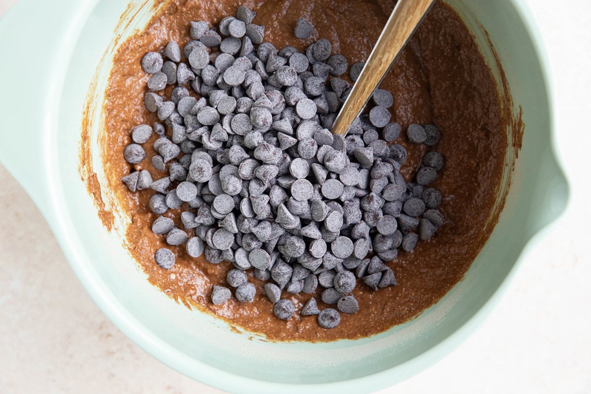 Chocolate chips on top of chocolate pumpkin bread batter, ready to be mixed in.