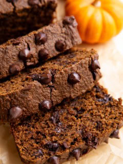 Loaf of chocolate pumpkin bread cut into slices on a sheet of parchment paper.