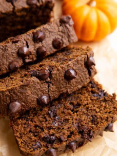 Loaf of chocolate pumpkin bread cut into slices on a sheet of parchment paper.