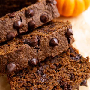 Loaf of chocolate pumpkin bread cut into slices on a sheet of parchment paper.