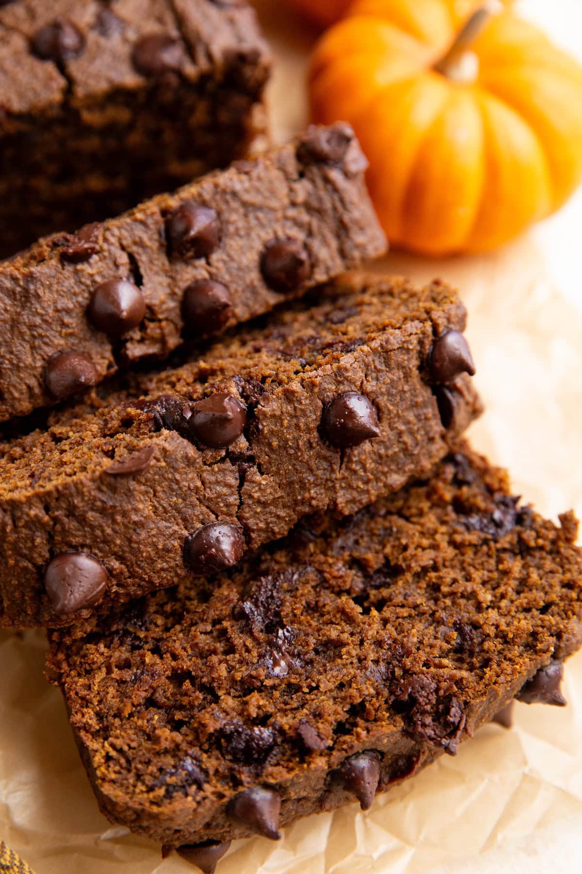 Loaf of chocolate pumpkin bread cut into slices on a sheet of parchment paper.