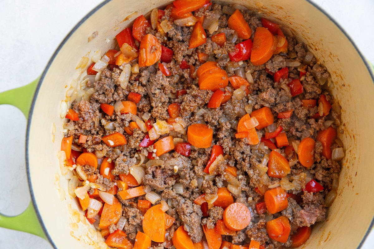 Ground beef, onion, garlic, bell pepper, and carrots cooking in a pot.
