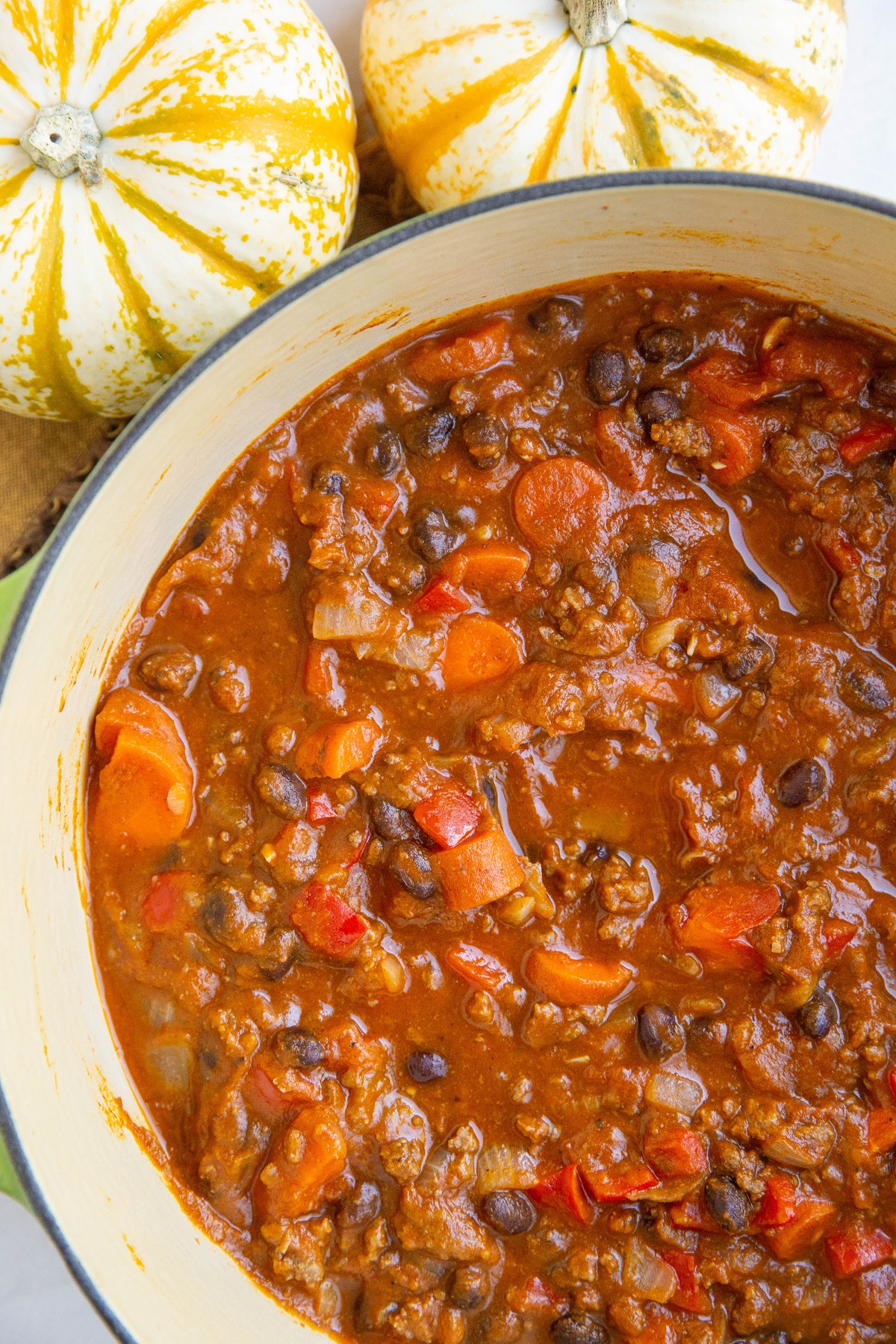 large pot of pumpkin chili with fresh pumpkins to the side.