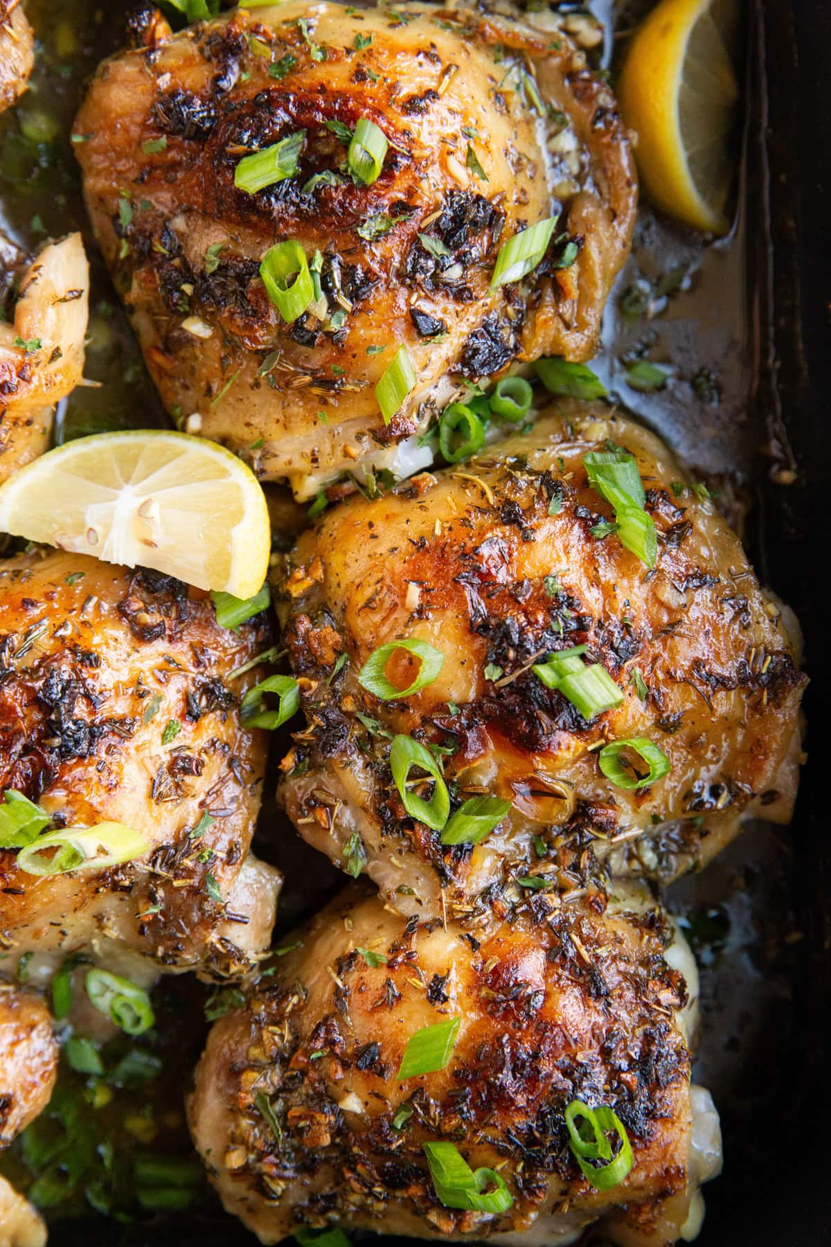 large roasting pan with garlic chicken thighs with green onions sprinkled on top, fresh out of the oven.