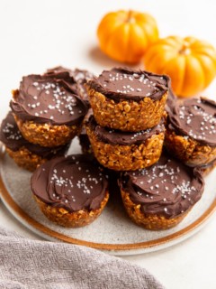 Plate of no-bake pumpkin cups with fresh pumpkins in the background.