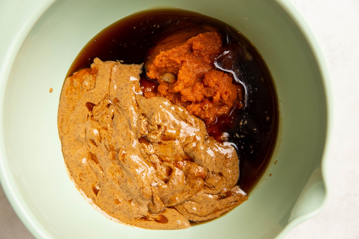 Wet ingredients for no-bake pumpkin oatmeal cups in a green mixing bowl, ready to be mixed.