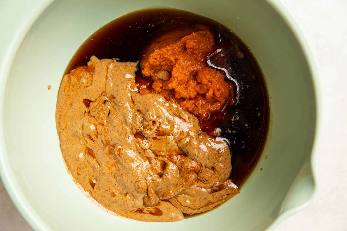 Wet ingredients for no-bake pumpkin oatmeal cups in a green mixing bowl, ready to be mixed.