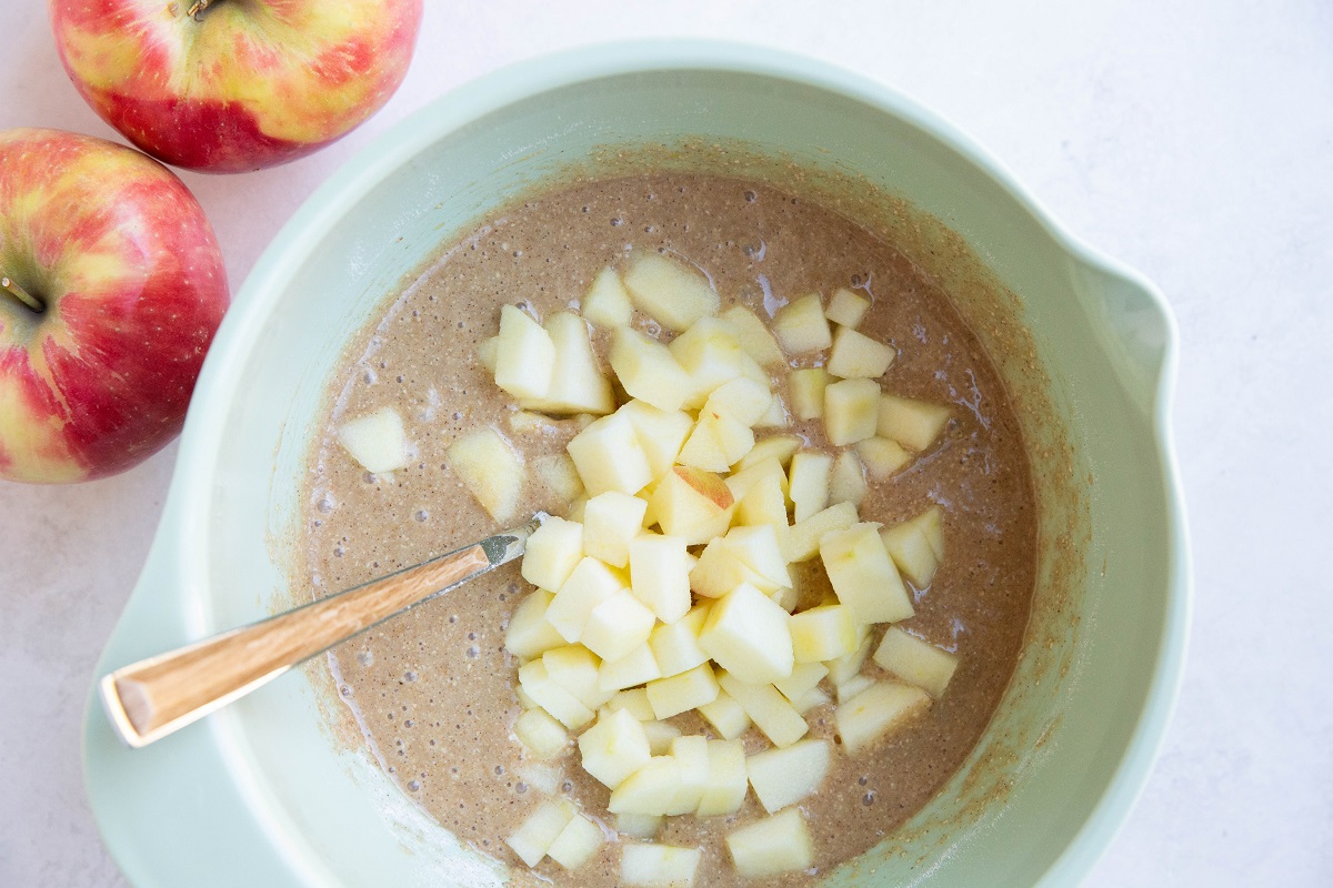 Chopped apple on top of cake batter to make apple cake.