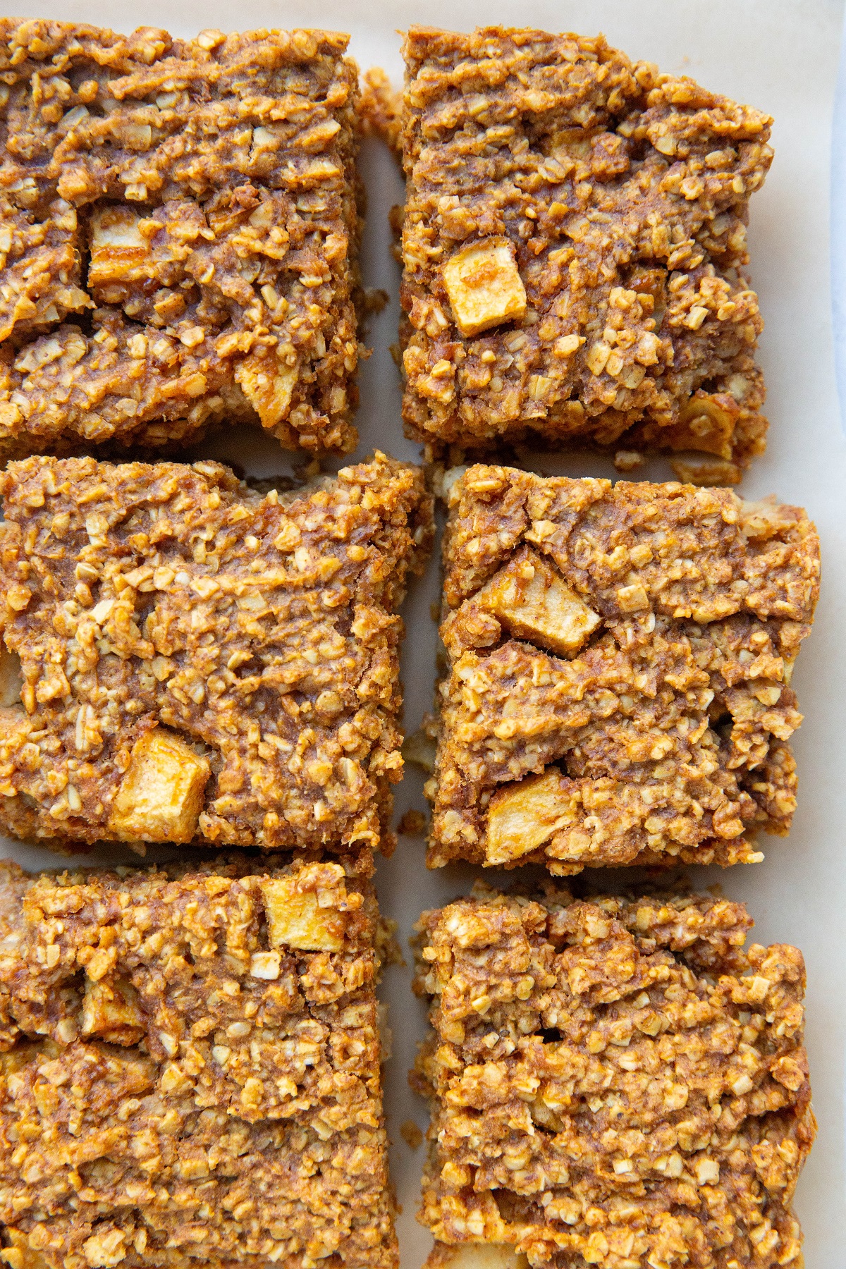 Apple pumpkin oatmeal bars on a sheet of parchment paper, cut into individual squares.
