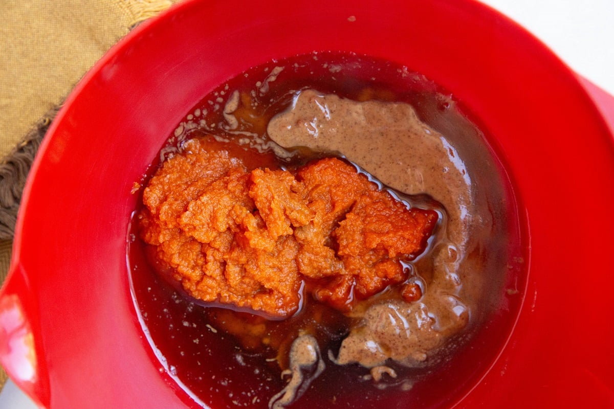 Wet ingredients for apple oatmeal bars in a red mixing bowl.